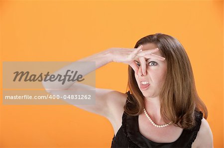 Attractive Caucasian woman pinches her nose and sticks out tongue