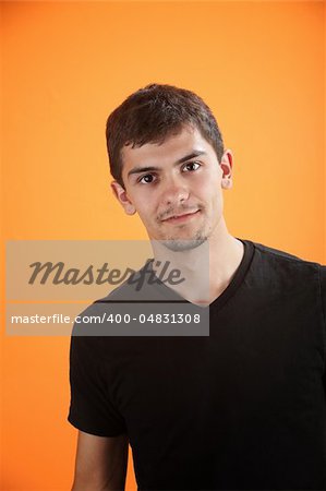 Confident and handsome Mexican American teen isolated on an orange background