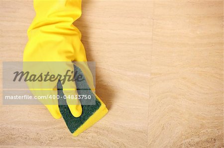 A picture of a hand in yellow gloves cleaning the floor