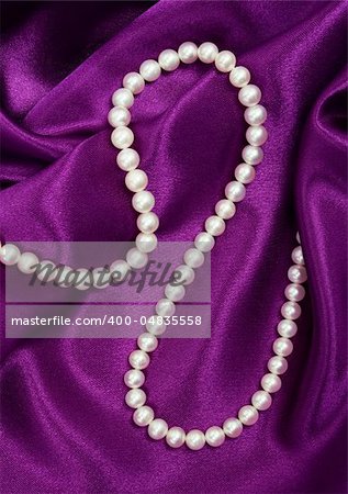 White pearls on a lilac silk as background