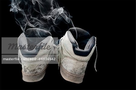 dirty old pair of sneakers on a black background