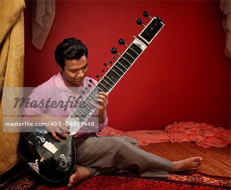 Handsome Indian man plays a Sitar indoors