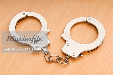 Metal handcuffs on the wooden background