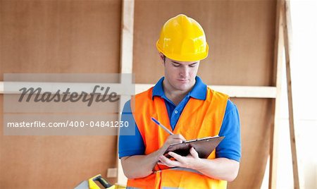 Self-assured male worker writing on a clipboard at work