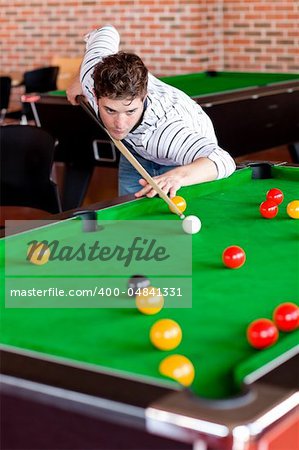 Concentrated young man playing snooker in a club