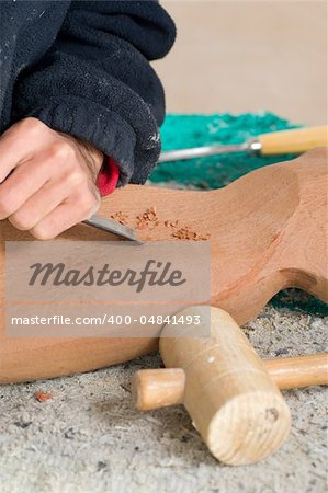 Sculptor working on a wooden statue in his studio