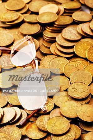 Many coins and reading glasses as business concept