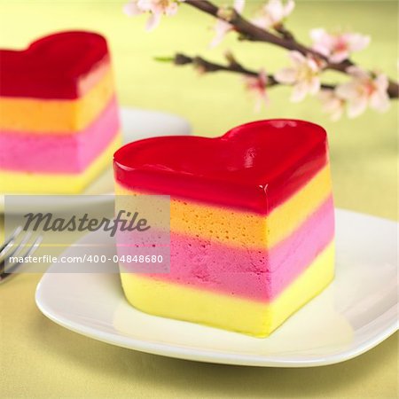 Colorful Peruvian heart-shaped jelly-pudding cakes called Torta Helada with a blooming peach branch in the back (Selective Focus, Focus on the front of the first cake)