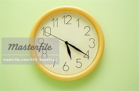 Yellow wall clock on the green background