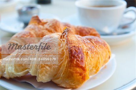 Breakfast with coffee and croissants in a basket on table