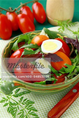 Fresh salad with tomato and quail eggs in  bowl on a green tablecloth