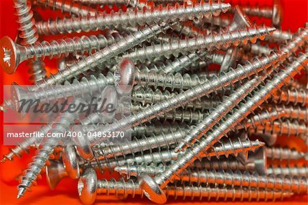 Closeup: metal screws on an orange background