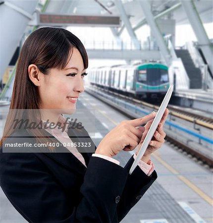 Young business woman using touch pad in the train station