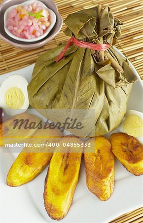 Traditional Peruvian food called Juane from the jungle area. It is a rice dish with meat and eggs covered by bijao leaves and served with fried plantains, eggs and olives (Selective Focus, Focus on the juane)