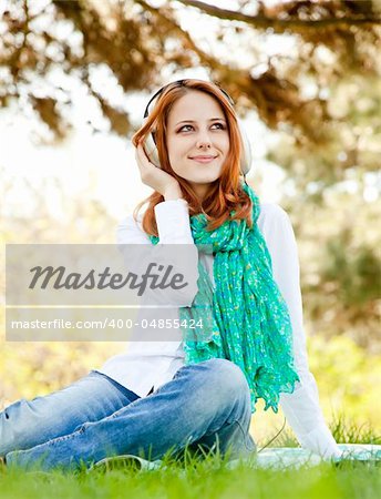 Redhead girl with headphone in the park.