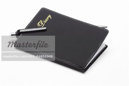 Black pocket diary and ballpoint pen on white background