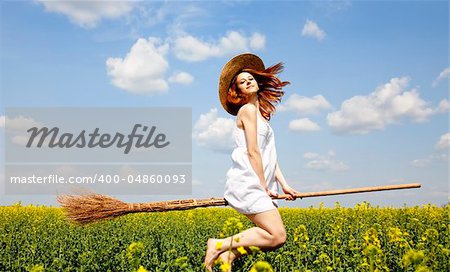 Redhead enchantress flying over spring rapeseed field on broom.