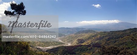 Beautiful panoramic valley of the sicilian hinterland under the majestic volcano Etna with dry river bed