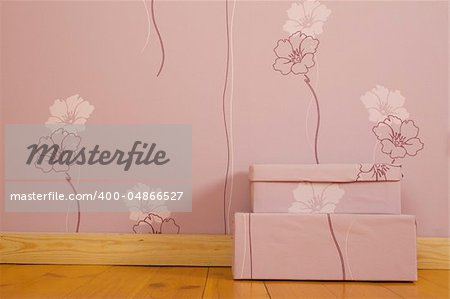 Purple wallpaper with flowers and a wooden floor in the room. On the floor there are two purple boxes