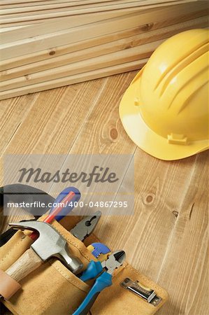 Construction background. Yellow helmet and tool belt on wooden floor.