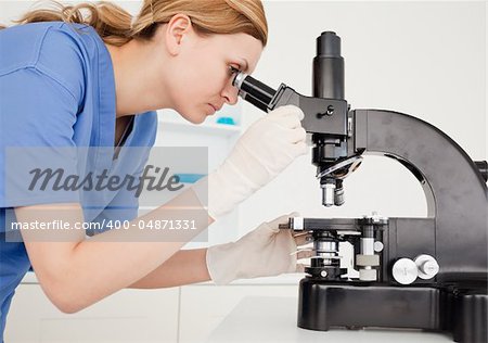 Female scientist conducting an experiment looking through a microscope in a lab