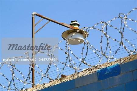 Barbed wire and lamp against the blue sky