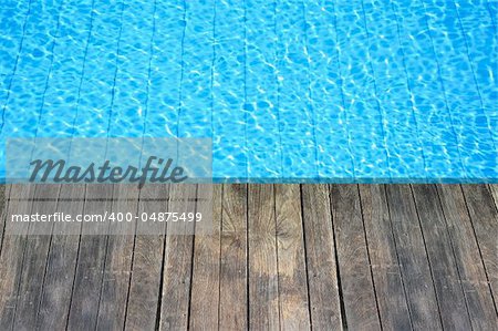 wood floor beside the blue swimming pool