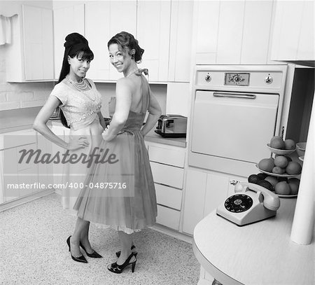 Happy Caucasian housewives in a retro kitchen with hand on hips