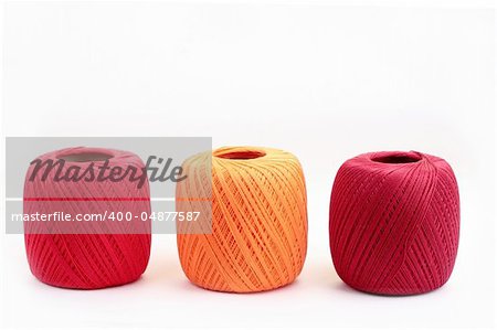 Red, yellow and purple coton spools against white background