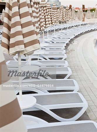 Swimming pool area of hotel with umbrella and beach chair .