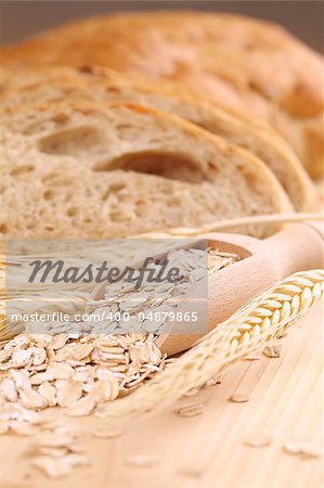 Close-up of a wooden scoop with oats and fresh bread in background