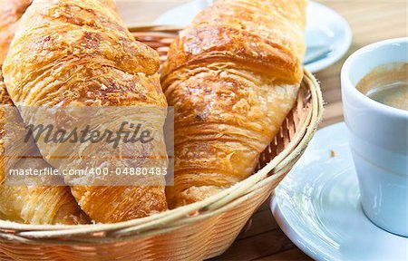 Breakfast with coffee and croissants in a basket on table