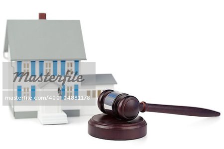 Grey toy house model and brown gavel against a white background