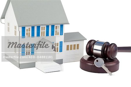 Grey toy house model with a key and a brown gavel against a white background