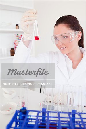 Pretty red-haired woman holding a test tube in a lab