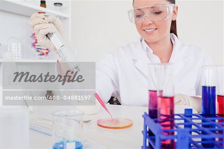 Pretty red-haired scientist using a pipette in a lab