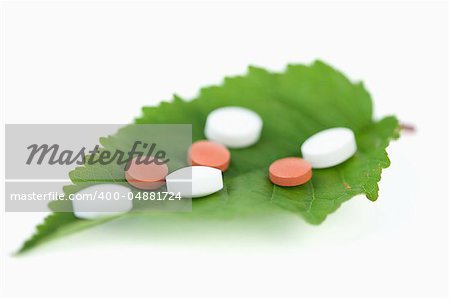 Pills on a leaf against a white background