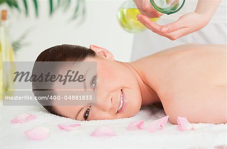 Beautiful woman getting massage oil on her back in a spa