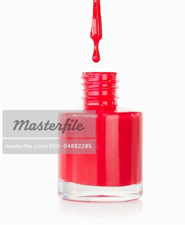 Portrait of a red nail polish droping in its flask against a white baqckground