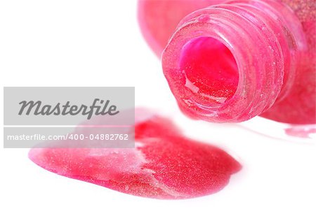 Close-up of open nail polish bottle and poured rose polish on white background. Shallow depth of fields. Focus on bottleneck.