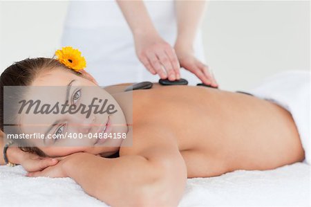 Close up of a delighted woman having a hot stone massage while looking at the camera