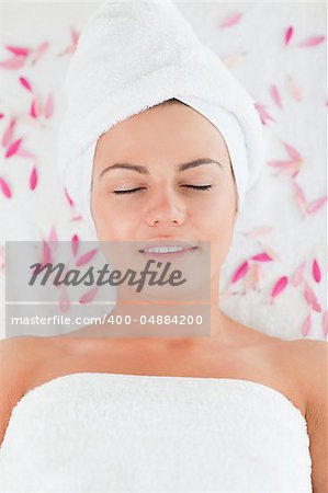 Beautiful brunette surrounded by petals in a spa
