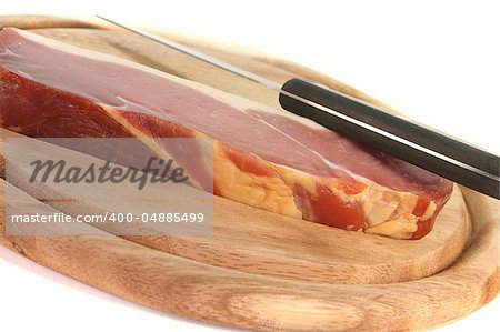 smoked bacon with a knife on a wooden board