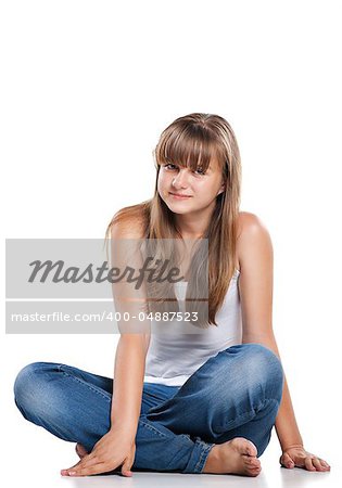 Smiling teenager girl sitting in studio on white background