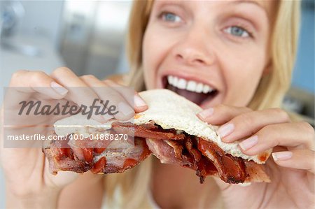 Mid Adult Woman Eating Bacon Sandwich