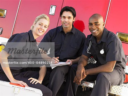 Three paramedics chatting and doing paperwork, sitting by their