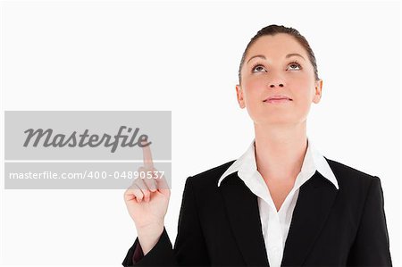 Charming woman in suit pointing at a copy space while standing against a white background