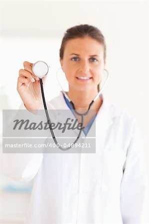 smiling doctor showing stethoscope looking into the camera in her surgery