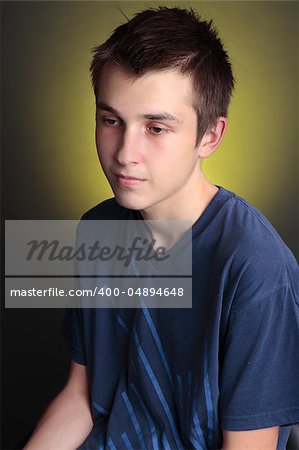 A boy sitting with a downcast face.  Depression, unhappiness, lonliness, etc