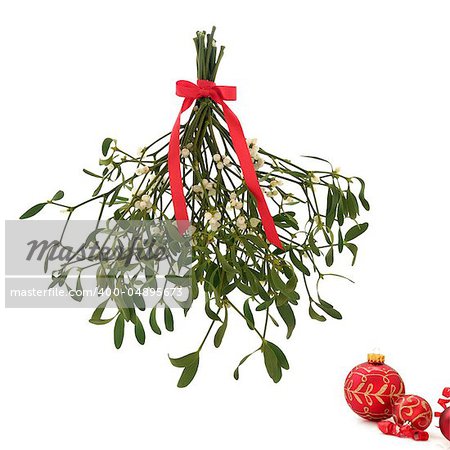 Mistletoe with berries and tied with a red bow with christmas baubles to one side, isolated over white background.